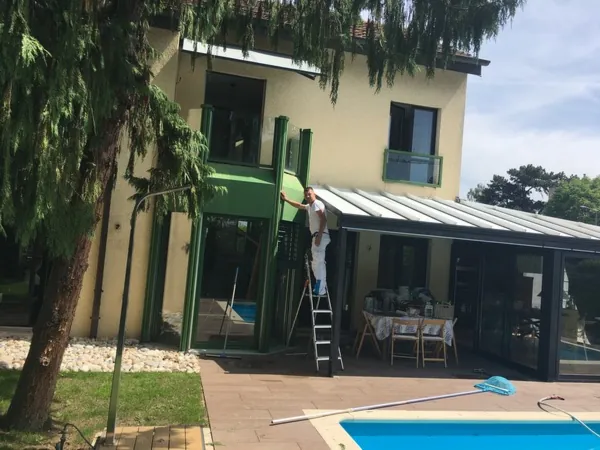 Véranda, auvent et boiseries au bord d’une piscine, en cours de peinture