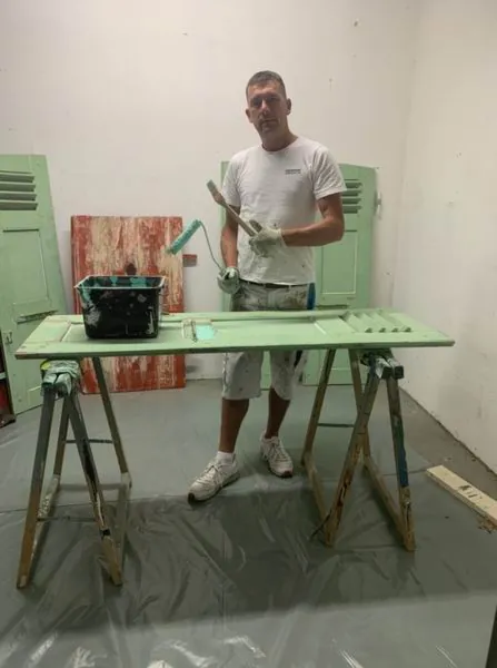 Un volet sur deux tréteaux à l’atelier, sol couvert