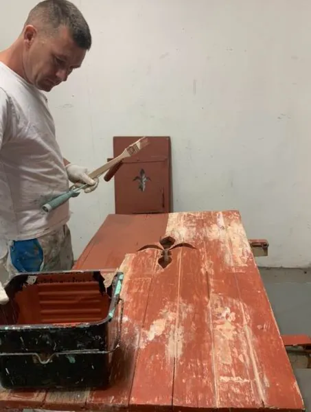Volet rouge posé sur l’établi, la peinture enlevée par endroits