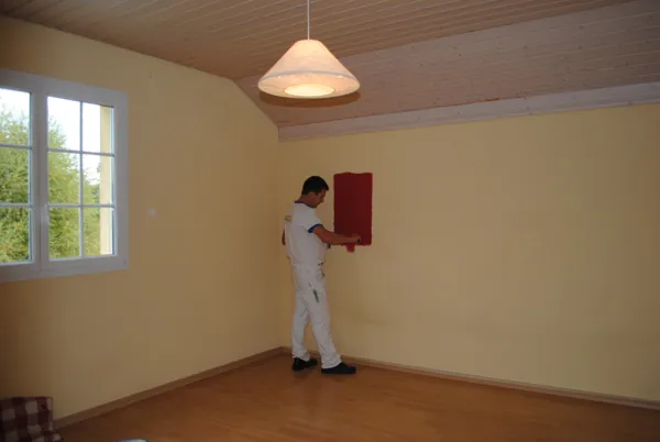 Un seul mur en rouge dans un séjour clair, parquet couvert