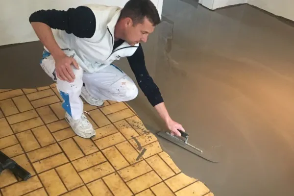 Enduit étalé à la lisseuse sur un vieux carrelage jaune