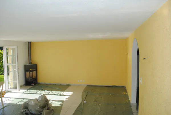 Mur jaune vif derrière un poêle, sol encore bâché