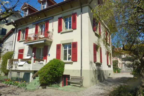 Volets rouges d’un chalet à la façade claire, après peinture